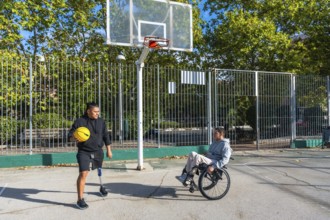 Disabled men, one using a wheelchair and the other wearing a prosthetic leg, playing basketball on