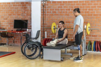 Two adaptive athletesone with a prosthetic leg and one using a wheelchairsupport each other during