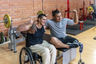 Two smiling men, one using a wheelchair and the other a prosthetic leg, warmly embracing each other