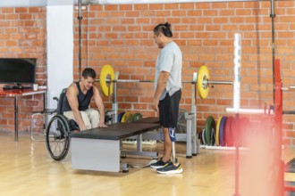 Adapted athletes focusing on their fitness routine at a gym, with one man using a wheelchair and