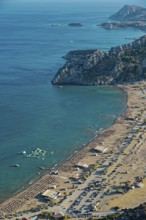 View of the sunny coastal landscape of Tsambika with sandy beach, blue sea and cliffs, Church of