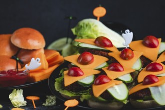 Burger buns with cheese, tomatoes, salad and Halloween decorations