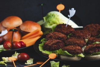 Burger buns with patties, salad, ingredients and Halloween decoration