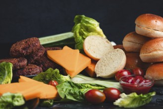 Meatballs and cheese on a bed of lettuce with burger buns and fresh vegetables