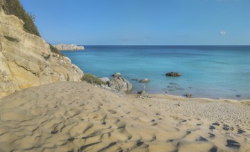 Tsambika beach with fine sand and large rocks on a sunny day, azure blue water and clear sky,