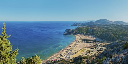 Coastal landscape of Tsambika with blue sea, wide beach and green hills under a clear sky, Tsambika