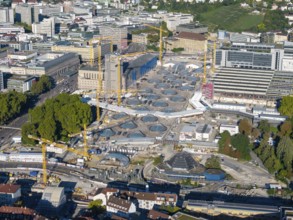 Spacious construction site with modern glass buildings and cranes in a sunny urban landscape, large