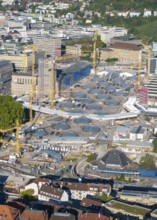 Large construction site in the city with numerous cranes and modern building structures on a sunny