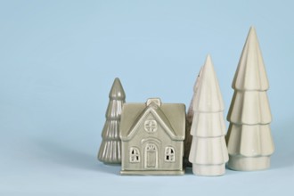 Light green ceramic Christmas trees and house on blue background
