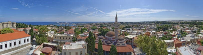 A sweeping panoramic view of the old town of Rhodes with a minaret and the sea in the distance,