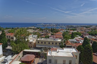 Overview of a town on the coast with harbour, many buildings and trees, Roloi Clock Tower, Medieval