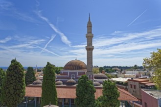 A minaret and domes in a tranquil cityscape with cypress trees and blue sky, Suleiman Mosque,