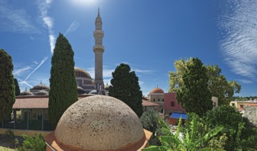 A minaret with domes and trees against a bright blue sky in a summer atmosphere, Suleiman Mosque,