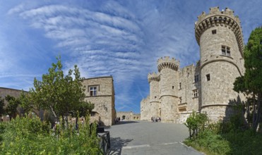 Wide view of a medieval castle with towers and stone walls under a cloudy sky, Grand Master's