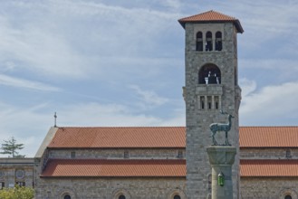 A church Ekklisia Evaggelismos with red roof and bell tower, in the foreground the deer cow statue