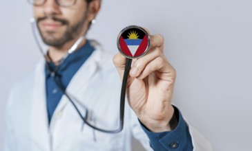 Doctor holding stethoscope with Antigua and Barbuda flag. Antigua and Barbuda health and care