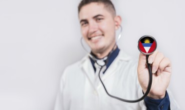 Doctor showing stethoscope with Antigua and Barbuda flag. Antigua and Barbuda national healthcare