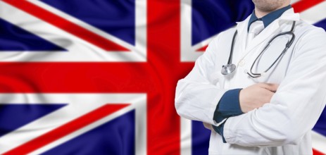 United Kingdom healthcare concept. Male doctor on United Kingdom flag. Doctor with crossed arms on