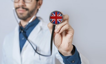 Doctor holding stethoscope with United Kingdom flag. United Kingdom health and care concept, United