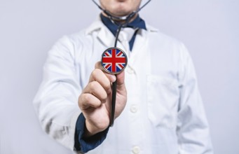 Doctor hands holding stethoscope with United Kingdom flag. United Kingdom health and care concept