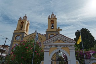 Yellow church with decorative entrance gate and bell towers against the sky, Greek Orthodox Church