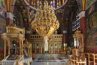 Richly decorated interior of an Orthodox church with icons and stained glass windows, Greek