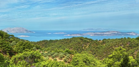Wide view of a dense forest and the blue sea with islands Chalki and Alimia on the horizon under a