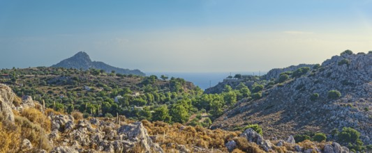 Hilly landscape near Stegna with green vegetation, sea view and blue sky, Stegna, Archangelos,