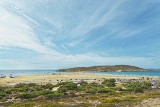 Spacious sandy beach of Prasonisi overlooking the sea and a small island under a blue sky with
