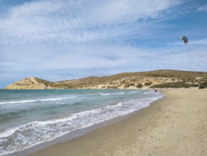 Quiet beach of Prasonisi with gentle waves and a kite in the sky under a slightly cloudy sky,