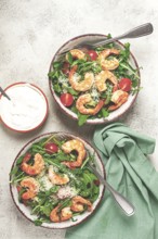 Two bowls of shrimp salad, arugula and cherry tomatoes, with parmesan cheese, healthy food