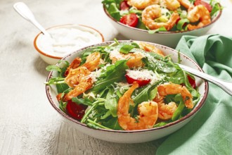 Two bowls of shrimp salad, arugula and cherry tomatoes, with parmesan cheese, healthy food