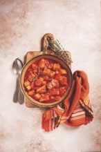 Meat goulash with potatoes and carrots, sweet peppers, in a saucepan, top view, traditional