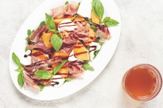 Salad with prosciutto and melon, with arugula and cheese, with balsamic sauce, natural light