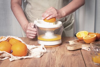 Preparation of freshly squeezed orange juice, using a juicer, in a cozy kitchen setting