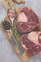 Freshly sliced beef legs, two ossobuco steaks, on a wooden board, with spices and herbs, ready to