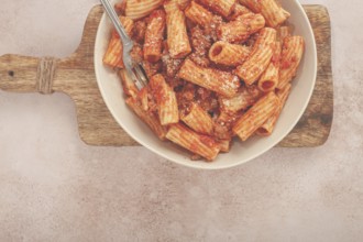 Rigatoni pasta with meat sauce and parmesan cheese on a light table, top view, homemade, no people