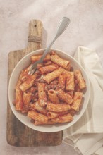 Rigatoni pasta with meat sauce and parmesan cheese on a light table, top view, homemade, no people