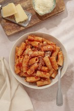Rigatoni pasta with meat sauce and parmesan cheese on a light table, top view, homemade, no people