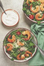 Two bowls of shrimp salad, arugula and cherry tomatoes, with parmesan cheese, healthy food