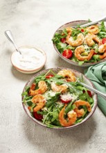 Two bowls of shrimp salad, arugula and cherry tomatoes, with parmesan cheese, healthy food