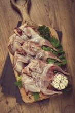 Raw quail meat, on a cutting board, with spices and herbs, top view