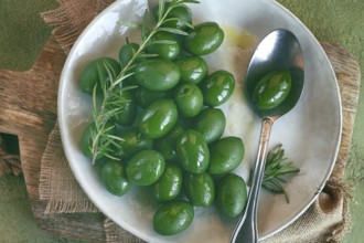 Chalkidiki olives, classic Greek green olive, on a plate, with a spoon, top view, no people