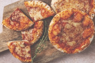 Four pizzetta Margaritas, on a cutting board, on a light gray surface, top view