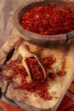 Spice saffron threads, in a wooden bowl, on a wooden table, top view, close-up