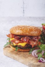 Burger with beef and bacon, with arugula and caramelized onions, pickles, sauce, homemade, no