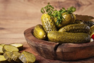 Pickled cucumbers in a wooden bowl with herbs and spices, close-up, rustic style