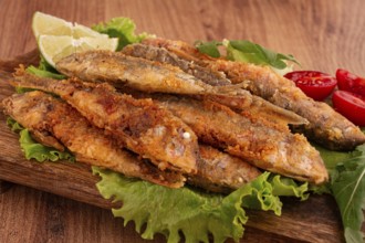 Fried crispy red mullet fish, on a wooden chopping board, with lime, no people