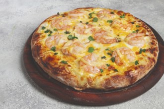 Four cheese pizza with shrimp and fresh microgreens, served on a wooden board, homemade, no people