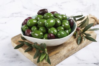 Chalkidiki olives, classic Greek green olives, in a bowl on a cutting board, top view, without